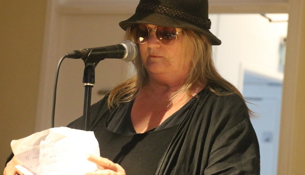 Dam i hatt och solglasögon läser poesi